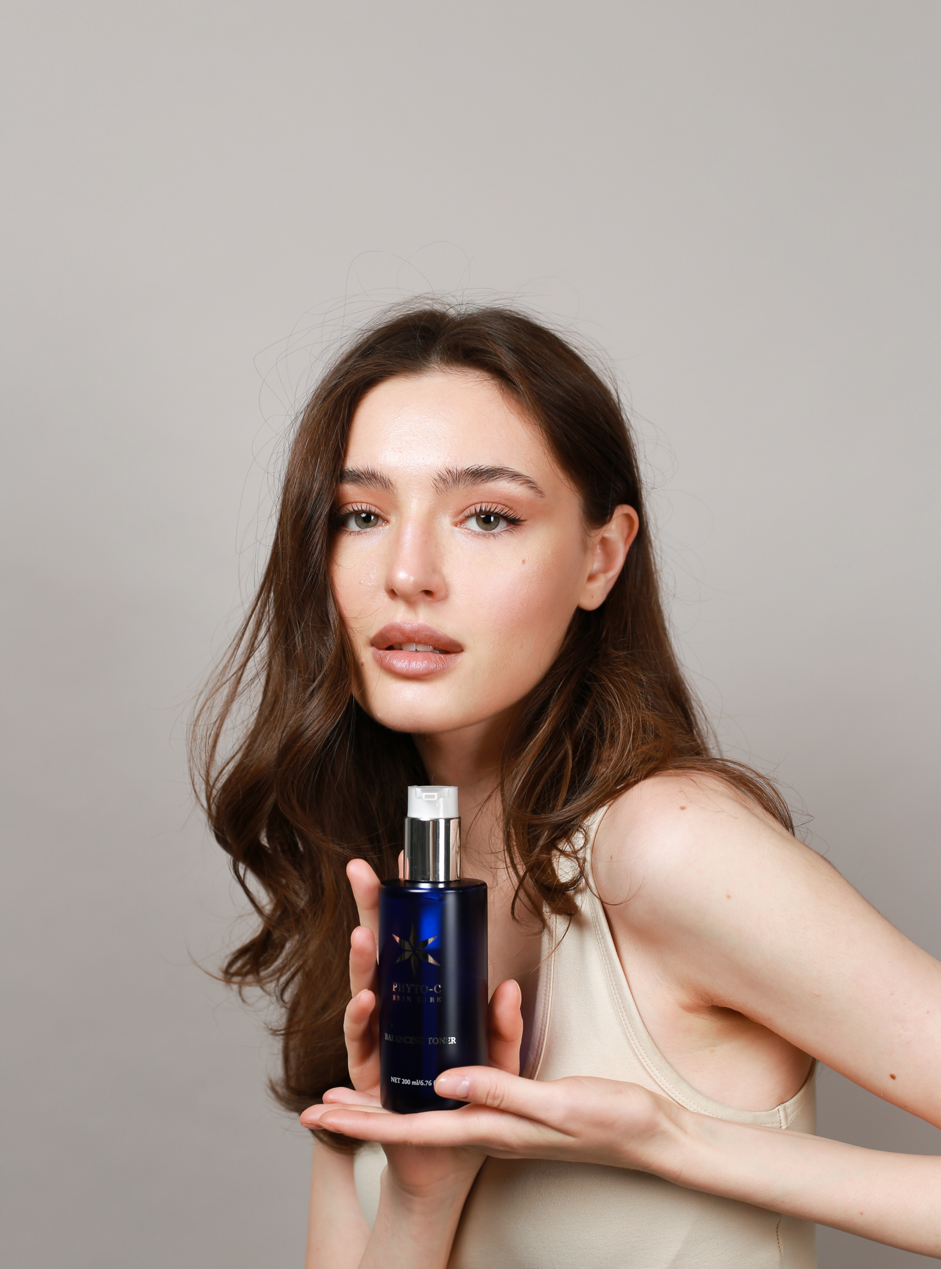 Тонік для обличчя Balancing Toner, модель тримає флакон